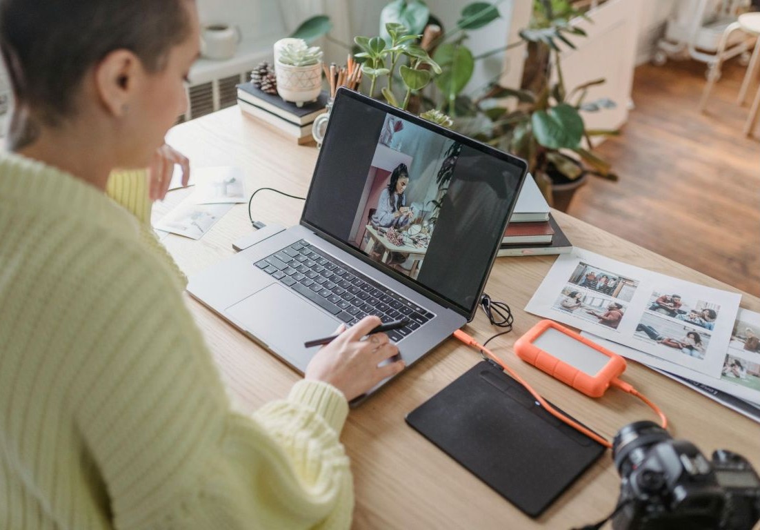 A woman sitting at her desk using a laptop. Image via Pexels 